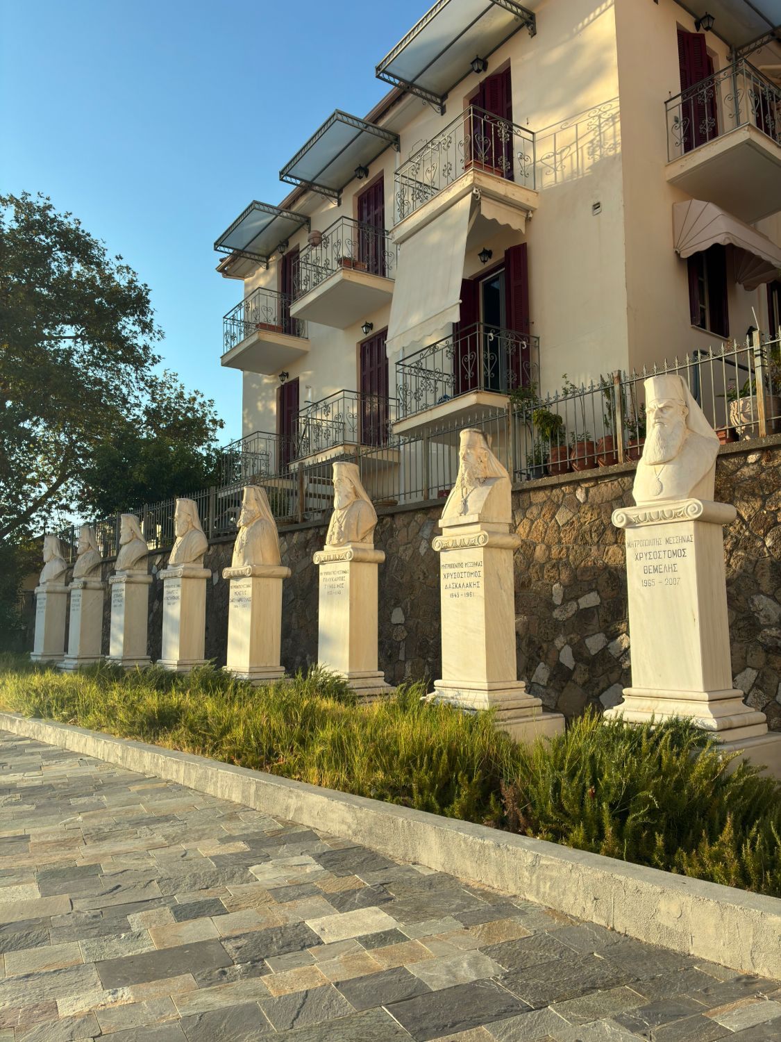 A row of white marble busts of former Metropolitans of Messinia on pedestals beside the Ypapanti Church in Kalamata