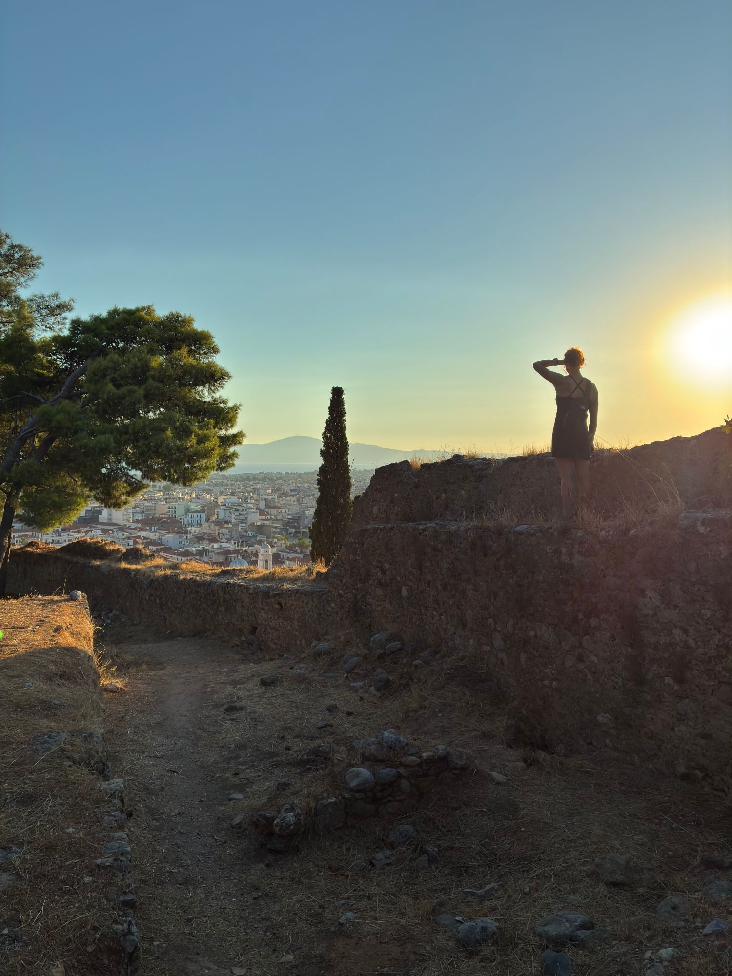 Kristine in silhouette on the old castle walls, looking out over Kalamata towards the sea as the sun sets