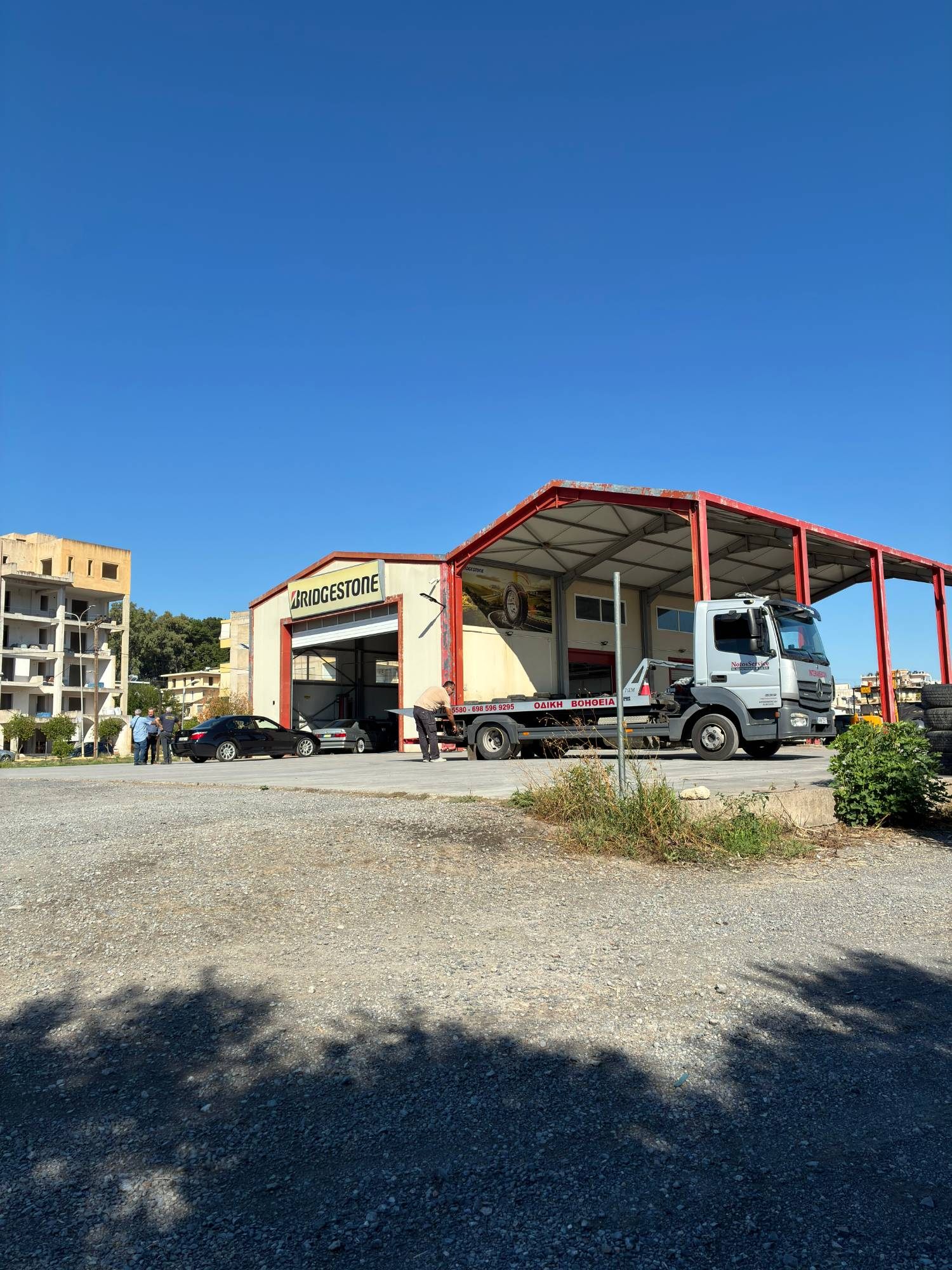 The roadside assistance tow truck outside a Bridgestone tyre workshop in Sparta under a clear blue sky