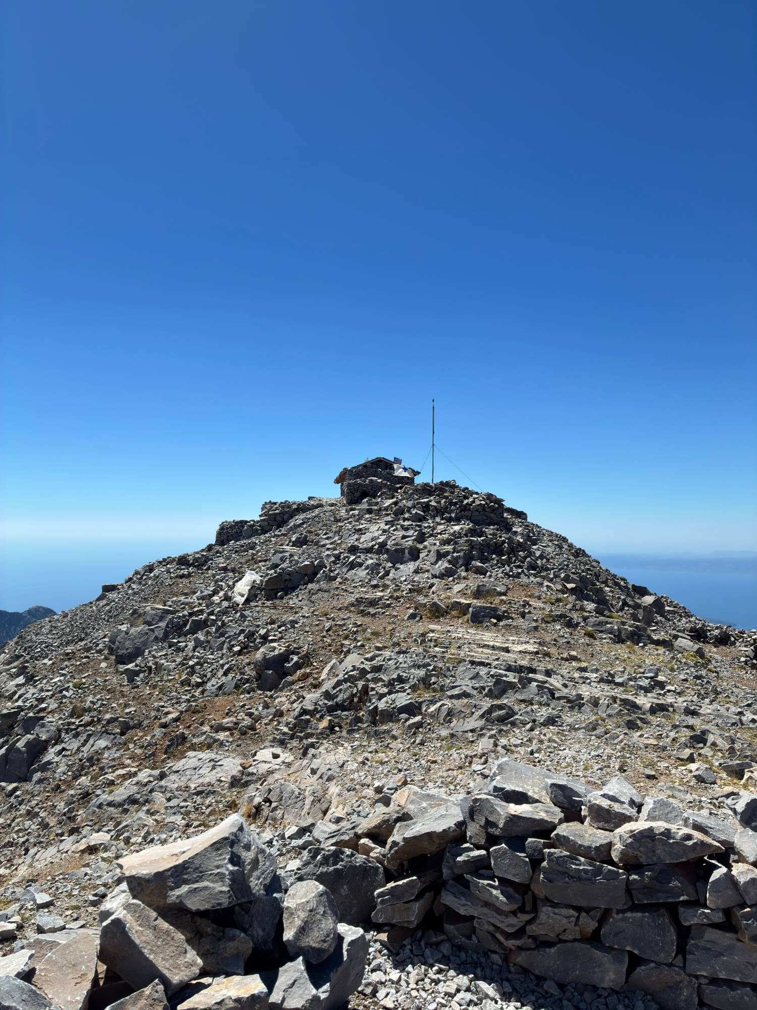 The last rocky stretch to the summit of Profitis Ilias, with the stone chapel and mast on top against a deep blue sky