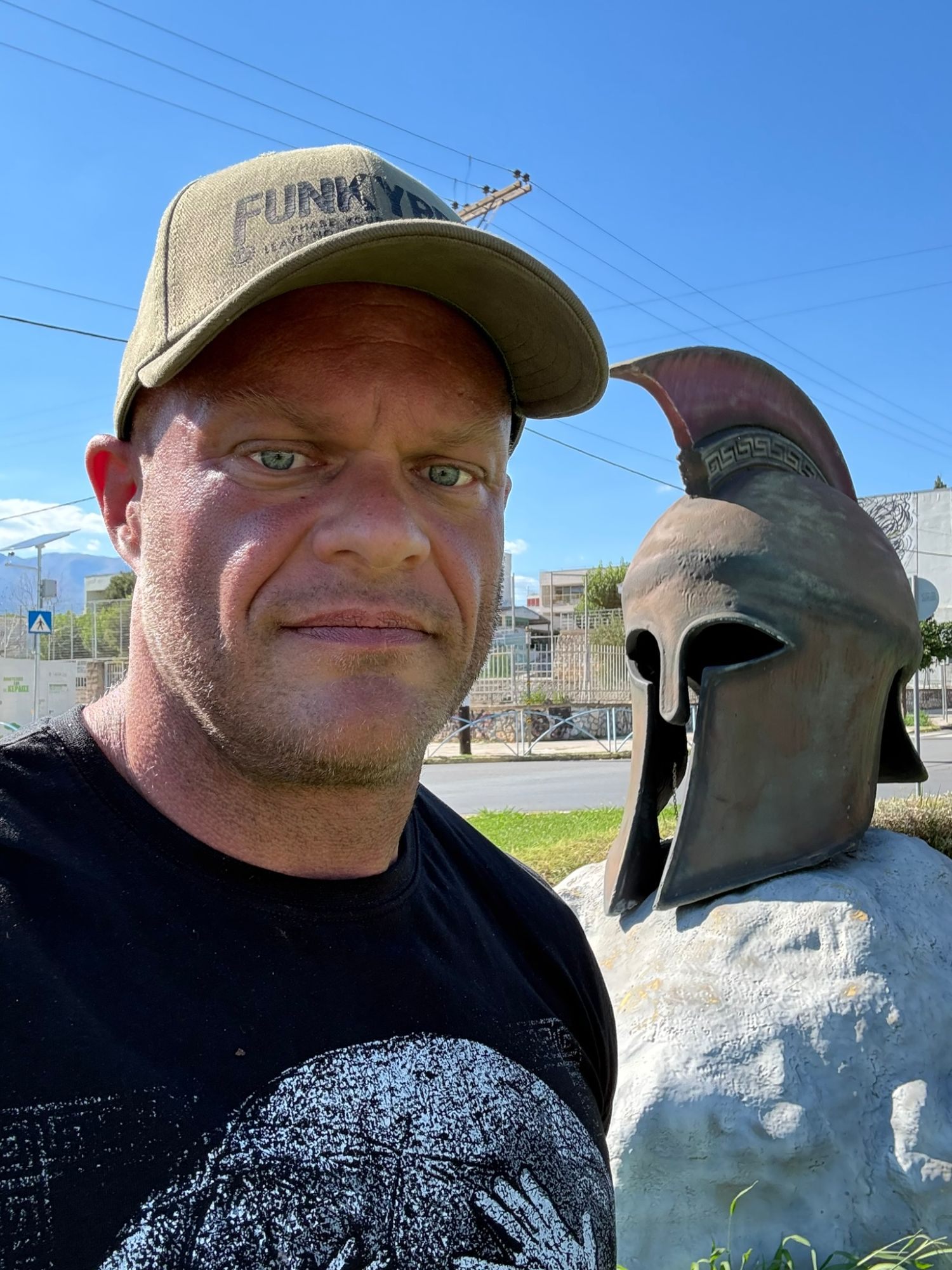 Selfie next to a sculpture of a Spartan helmet
