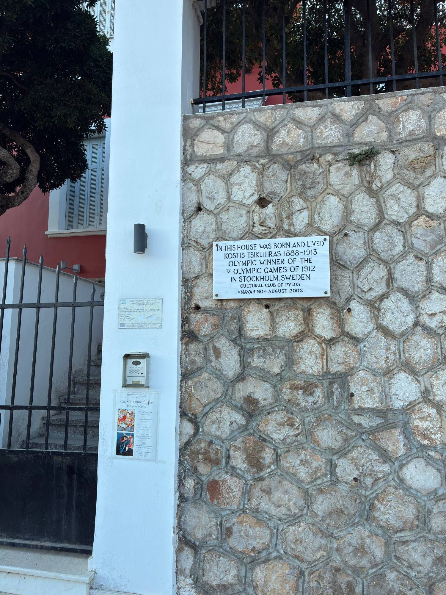 Marble plaque on a stone wall in Pylos saying that Olympic winner Kostis Tsiklitiras was born and lived in the house